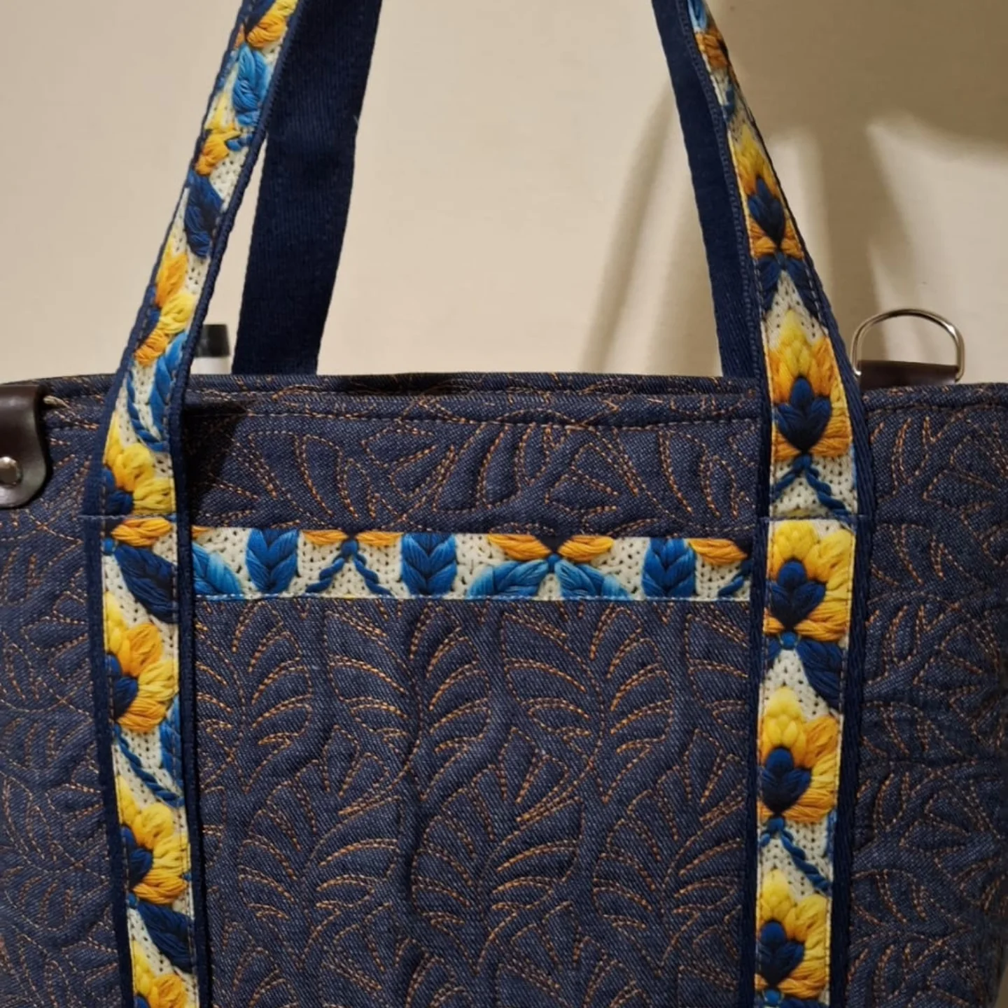Bolsa em jeans com aplicação de bordado floral azul e amarelo